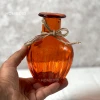 تصویر گلدان خمره ای رنگ نارنجی در دست.
