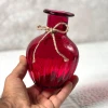 تصویر رنگ قرمز از گلدان خمره ای در دست.
