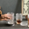 لیوان دمنوش شیشه ای در حالت خالی در دست قرار گرفته است.