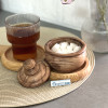 قندان چوبی خاص پر از قند در کنار یک لیوان چایی قرار دارد